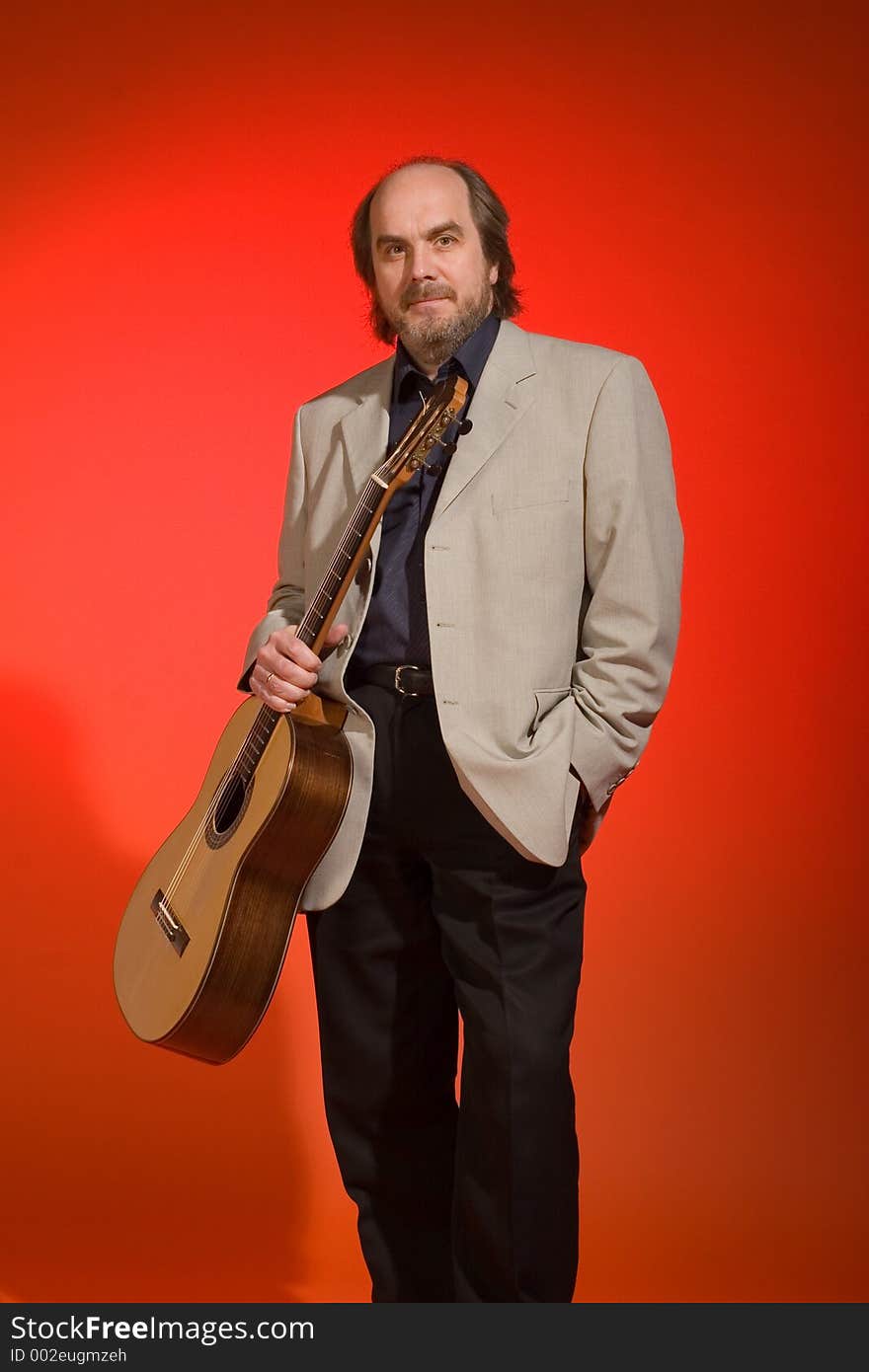 Middle aged man-musician with his guitar on a red background.