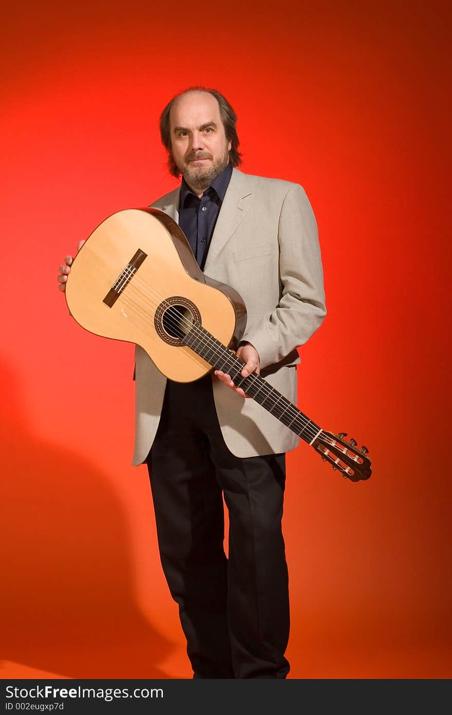 Middle aged man-musician with his guitar on a red background.