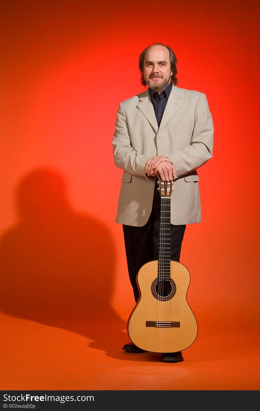 Middle aged man-musician with his guitar on a red background.