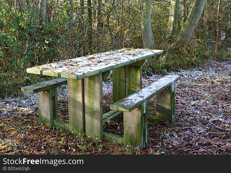 A picnic table in wooded area in winter. A picnic table in wooded area in winter