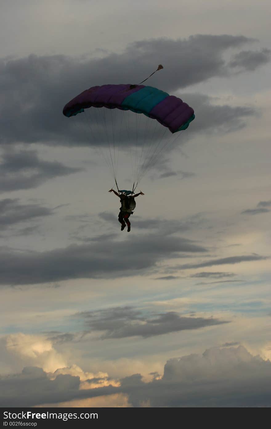 Silhouette of man ready for landing with parachute. Clouds background. Silhouette of man ready for landing with parachute. Clouds background.