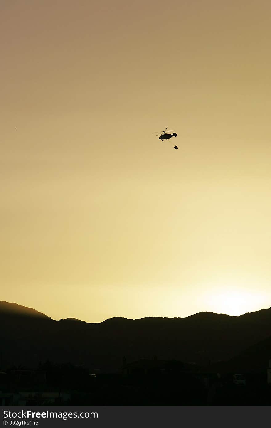 Firefighter helicopter flying over mountains to fire at sunset. Firefighter helicopter flying over mountains to fire at sunset