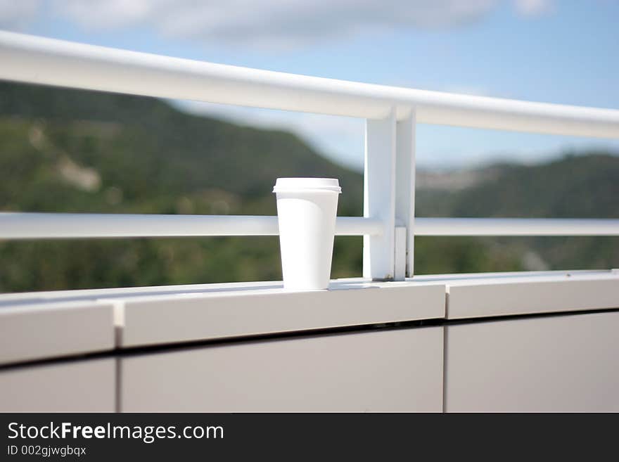 Cup on the wall, coffee cup, white, blur background, blue sky, water. Cup on the wall, coffee cup, white, blur background, blue sky, water