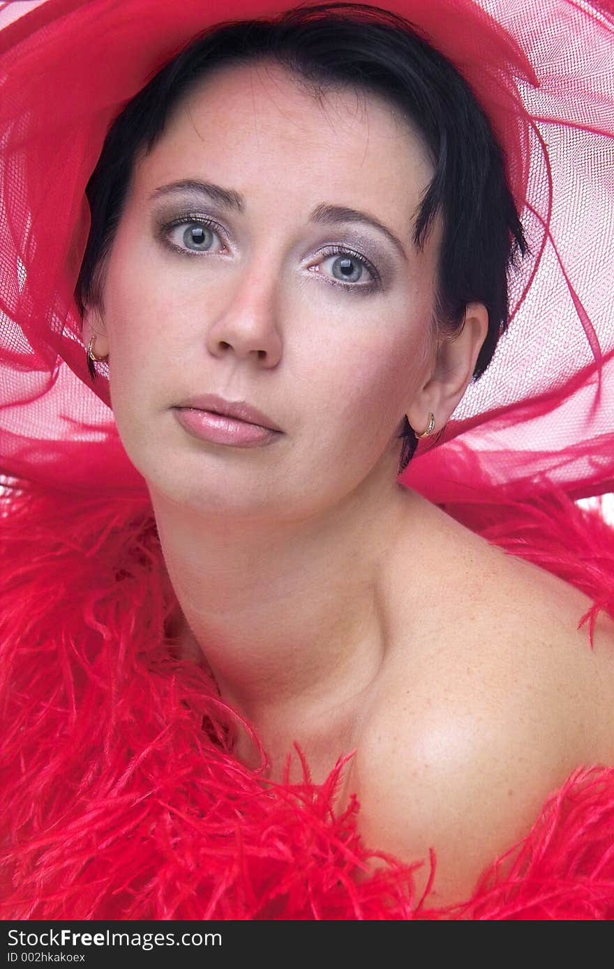 Portrait of a beautiful young woman wearing a red hat and feathered red boa over naked shoulders. Portrait of a beautiful young woman wearing a red hat and feathered red boa over naked shoulders