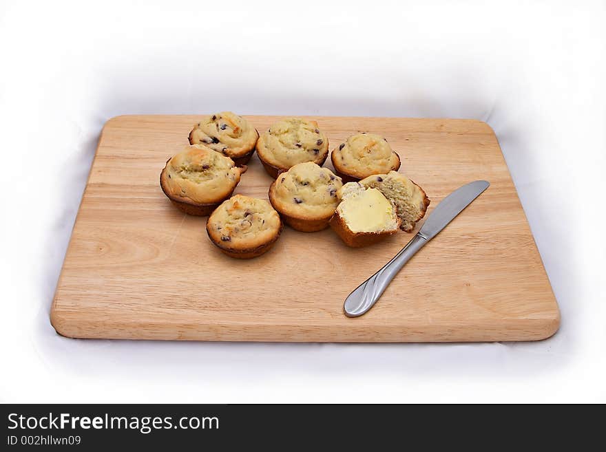 Freshly baked and buttered muffins on cutting board. Freshly baked and buttered muffins on cutting board.