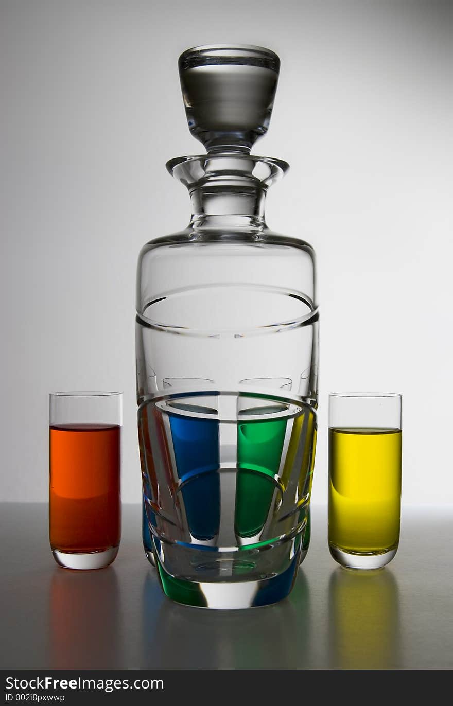 Large bottle with 4 glasses each with a different color. Large bottle with 4 glasses each with a different color