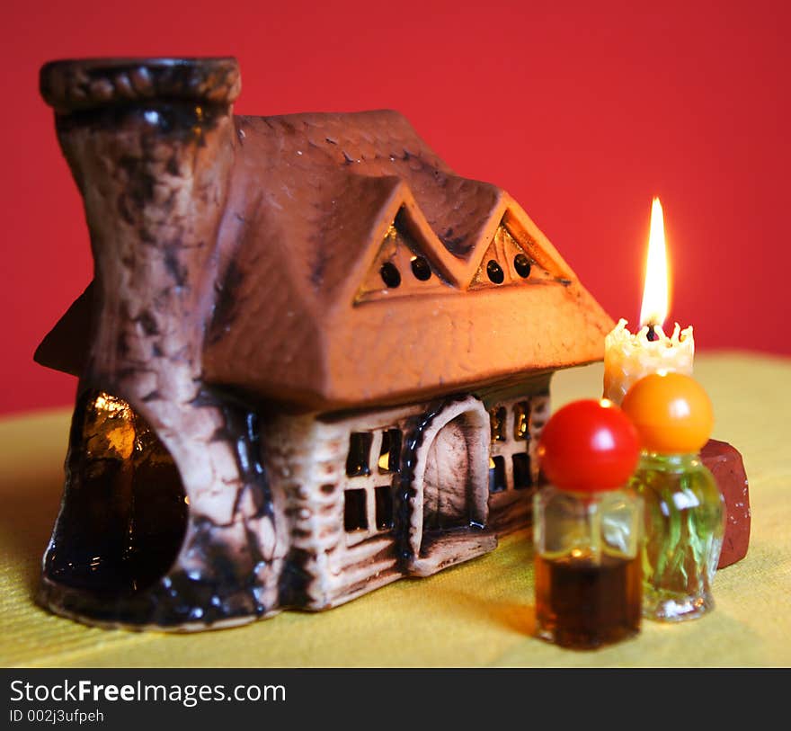 Composition with aromatic house. There is a candle inside the house which is heating the aromatic oil up. Composition with aromatic house. There is a candle inside the house which is heating the aromatic oil up.