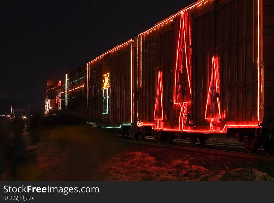 Train cars decorated with lights sitting at station while people walk by. Train cars decorated with lights sitting at station while people walk by