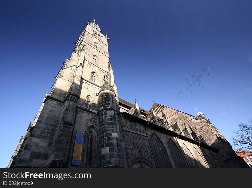 Old Building in Nuremburg market. Taken ground up using a wide ange lense. Birds are flying in background creating a motion blur.