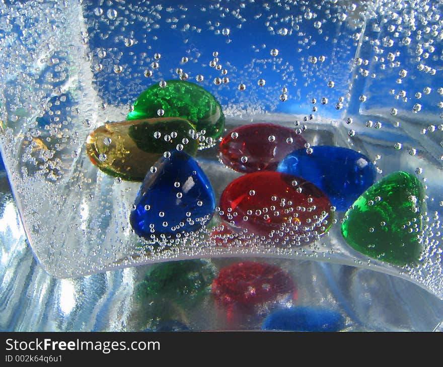 Small glass stones in a vase filled by the mineral water. Background. Small glass stones in a vase filled by the mineral water. Background