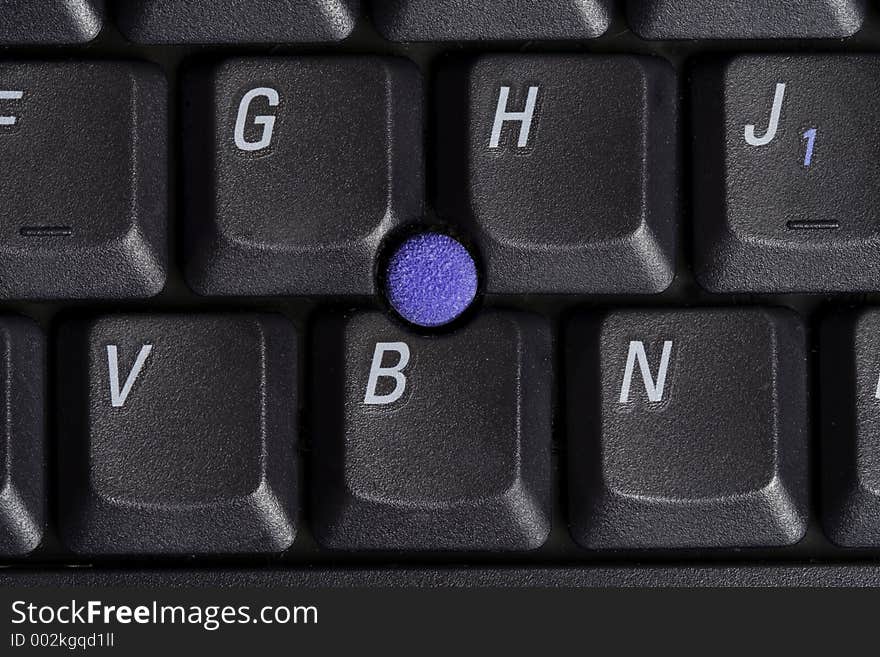 Macro shot of laptop keyboard with point stick surrounded by some keys.