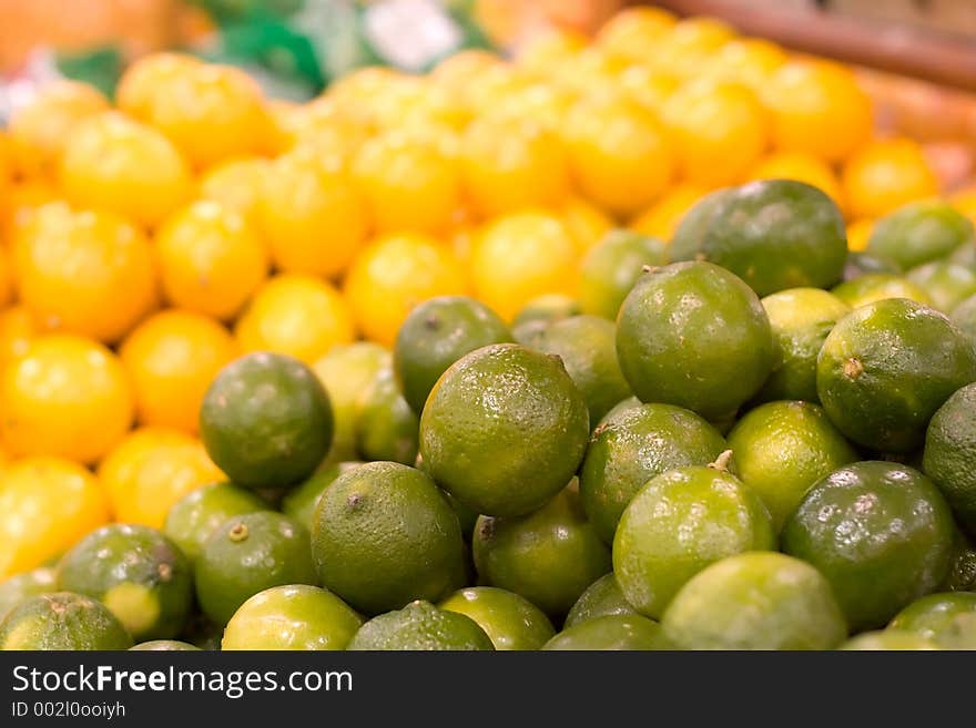 A pile of limes in focus against a blurred background of lemons. Shot at the local grocery store. A pile of limes in focus against a blurred background of lemons. Shot at the local grocery store.