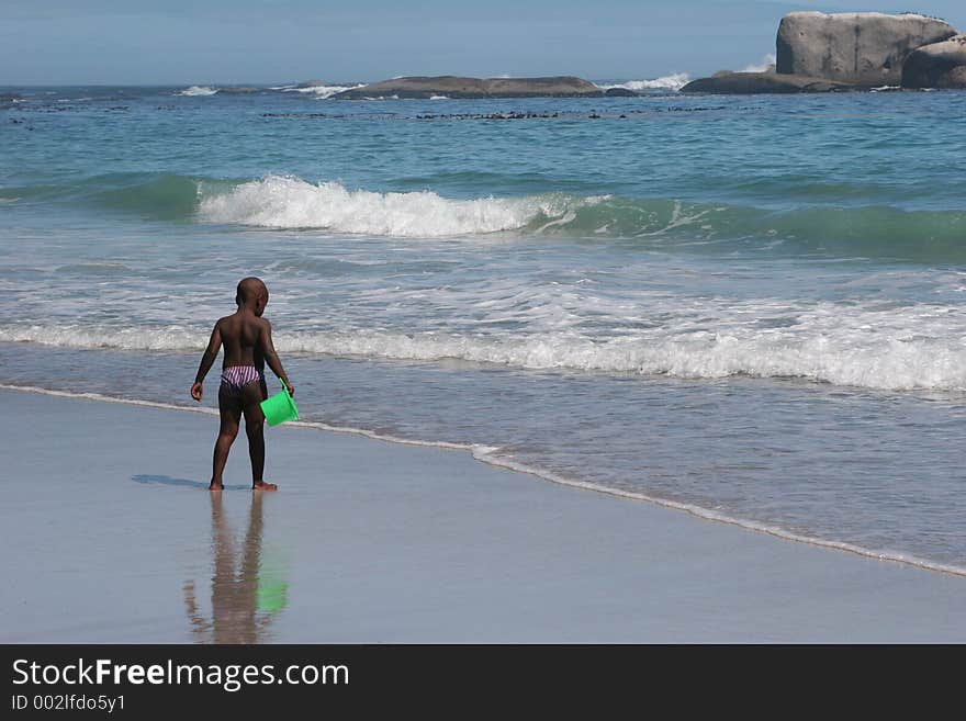 Clifton beach, South Africa,boy with a green bucket in his hand. Clifton beach, South Africa,boy with a green bucket in his hand