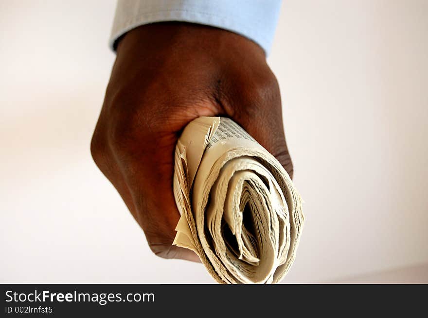 This is an image of a newspaper, folded and held by a black person. This is an image of a newspaper, folded and held by a black person