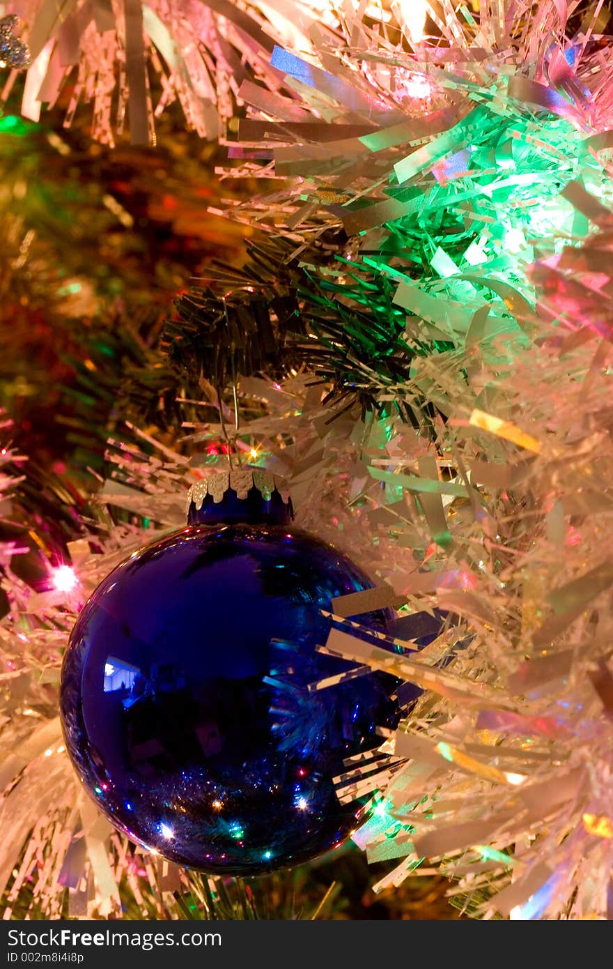 A blue Christmas tree ornament surrounded by garland. A blue Christmas tree ornament surrounded by garland.