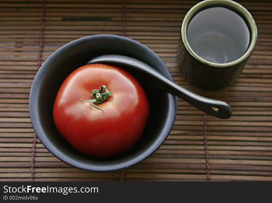 Tomato in a black bowl and a japanese teacup. Tomato in a black bowl and a japanese teacup