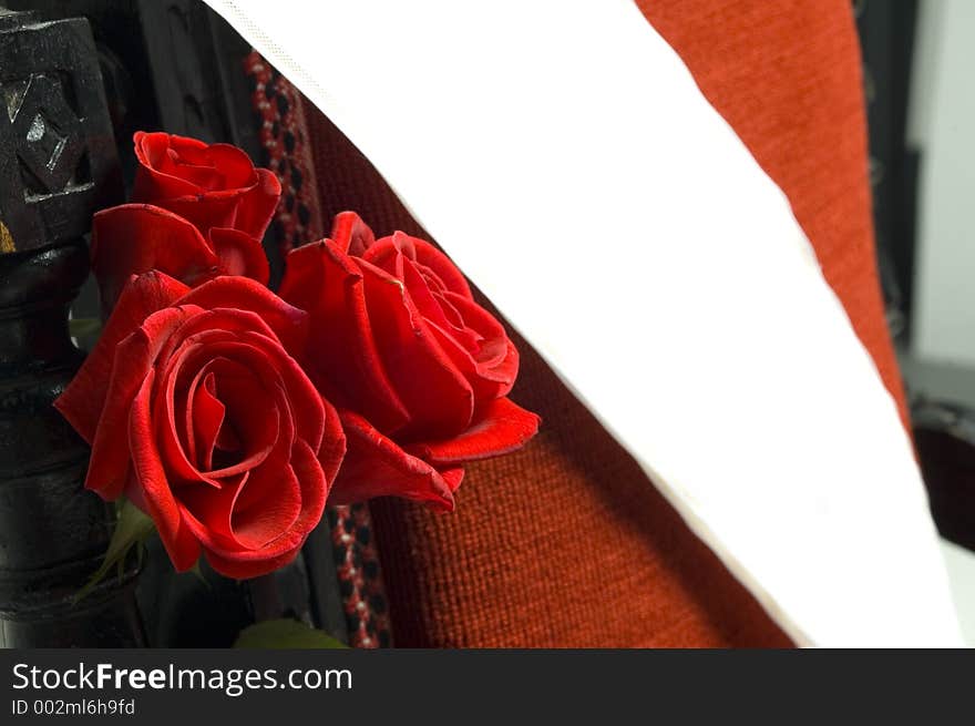 Red roses and a blank white ribbon resting on a red luxurious armchair. Abstract composition, works well for wedding, princess, miss, or other elections theme. Red roses and a blank white ribbon resting on a red luxurious armchair. Abstract composition, works well for wedding, princess, miss, or other elections theme.