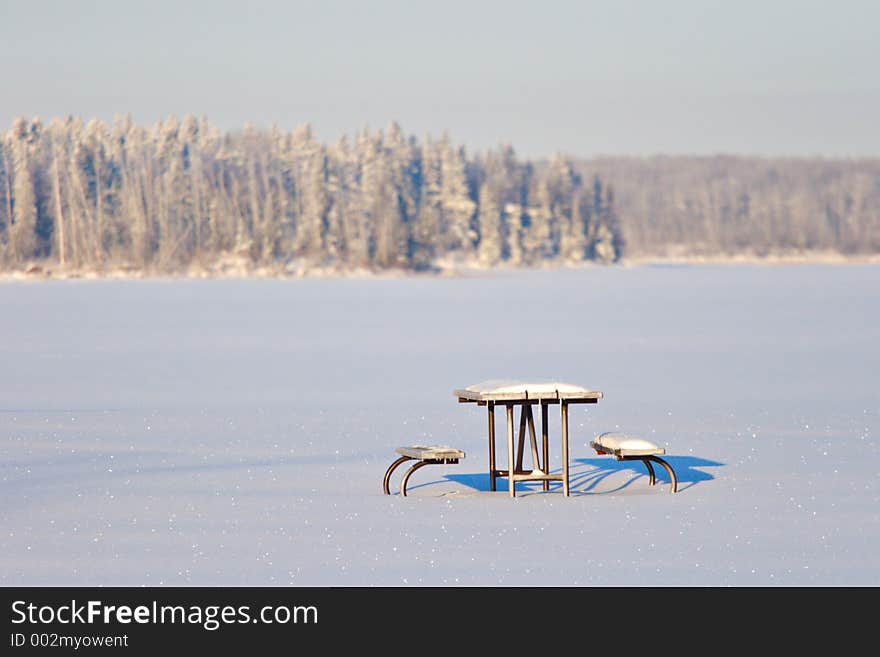 A snow covered picnic table waits for spring. A snow covered picnic table waits for spring.