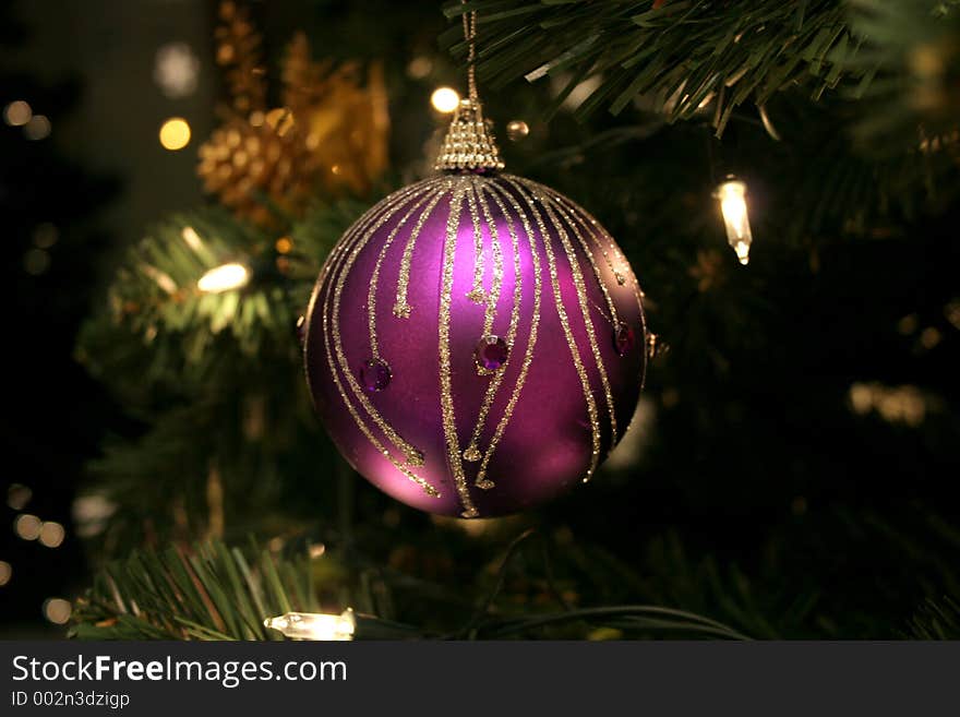 Elegant purple ornament (decorated with glitter and gems) on Christmas tree, surrounded by lights. Elegant purple ornament (decorated with glitter and gems) on Christmas tree, surrounded by lights.