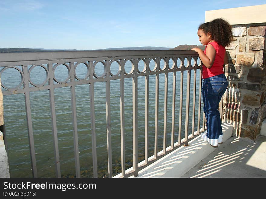 Pretty little girl looking out at the lake on a sunny day. Pretty little girl looking out at the lake on a sunny day.