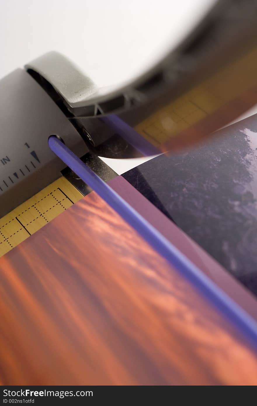 A paper cutter cutting two photos. Shallow depth of field.