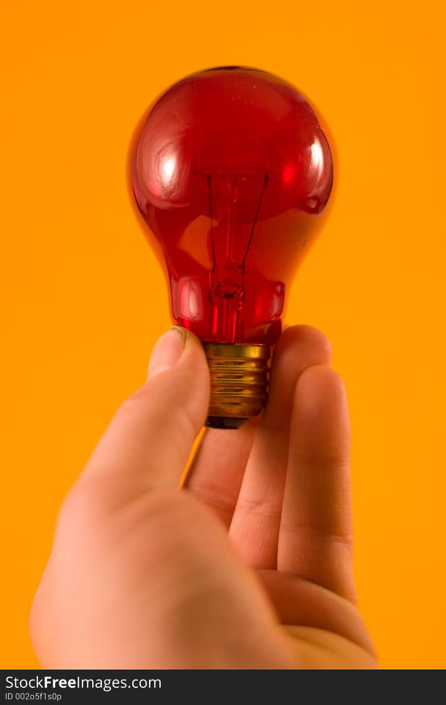 A red bulb held up against an orange background.