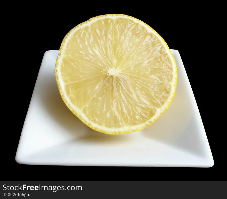 Half a lemon on a white mini dish, black background