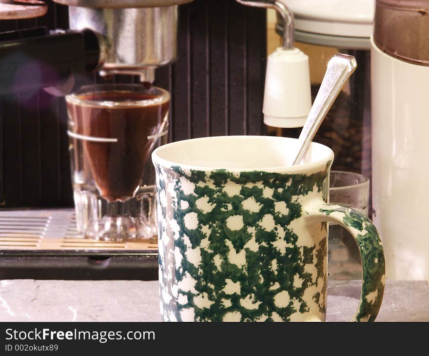 Close up photo of coffee cup with cappuccino maker in the background. Close up photo of coffee cup with cappuccino maker in the background.