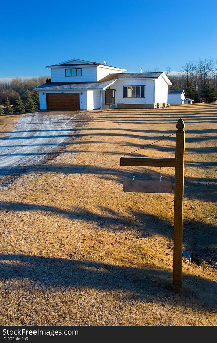 A rural home with a sign marking the entrance to the lot. A rural home with a sign marking the entrance to the lot.