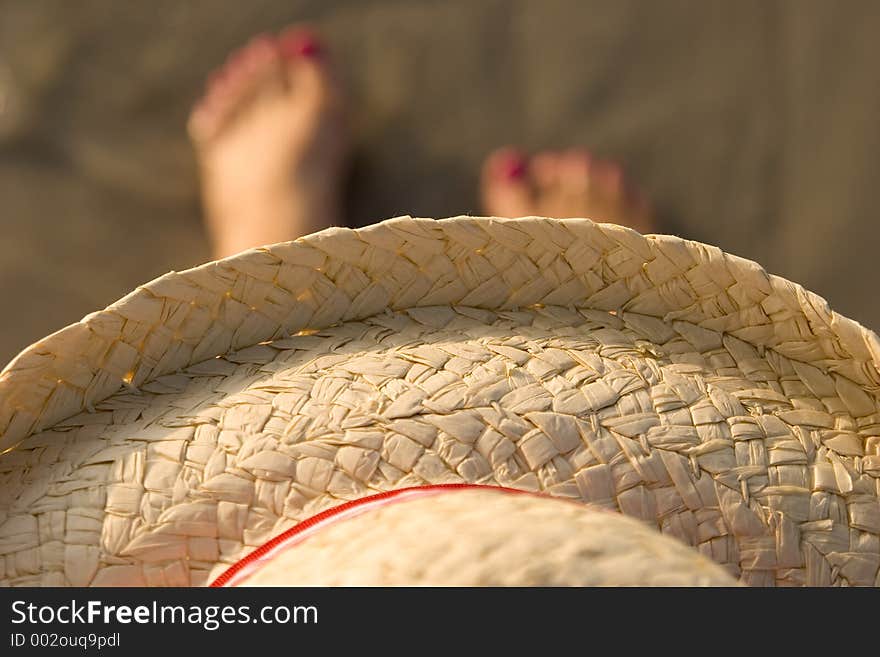 Picture of a straw hat on a women over her painted toes. Picture of a straw hat on a women over her painted toes