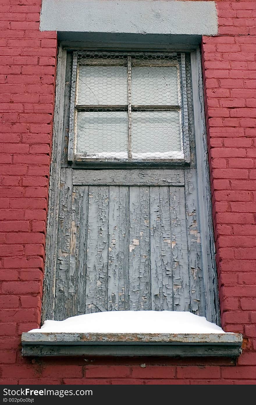 Paint peels from and old wooden door adjacent to newly painted brick