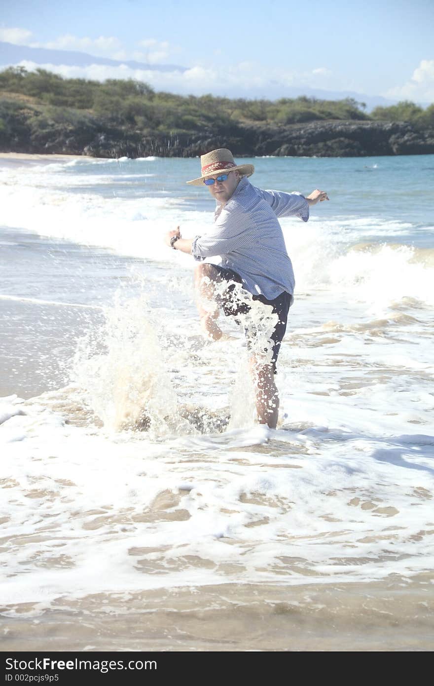 Man kicking up water on the beach. Man kicking up water on the beach