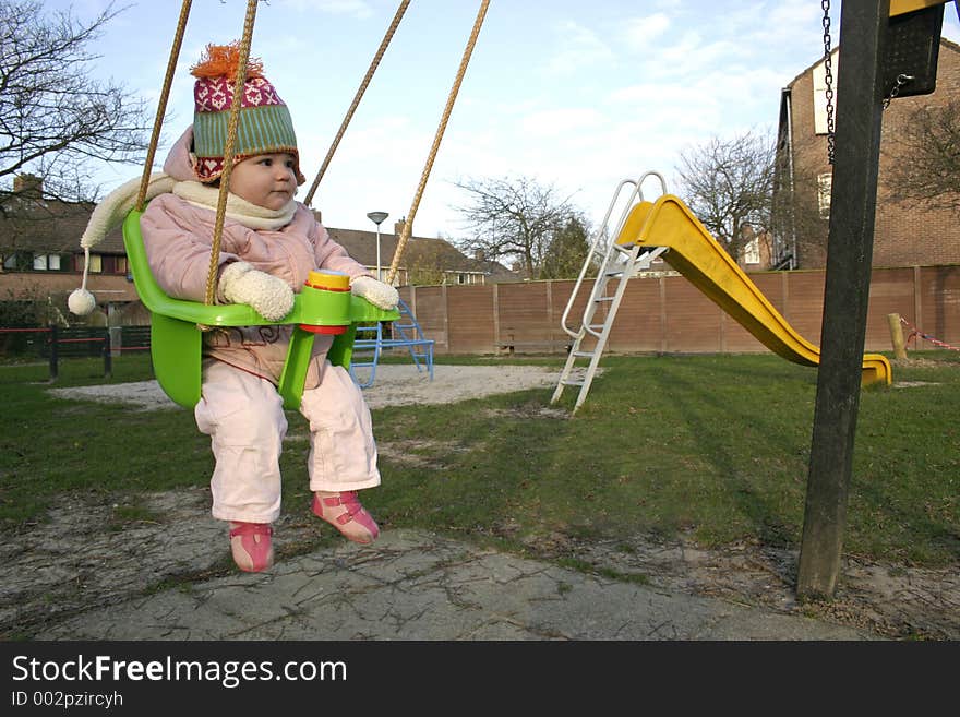 Little Girl on a swing at the playground in the winter time. Little Girl on a swing at the playground in the winter time.