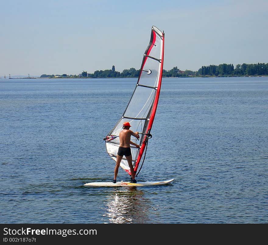 Photo of a windsurfer on the sea, taking his first lessons. Photo of a windsurfer on the sea, taking his first lessons