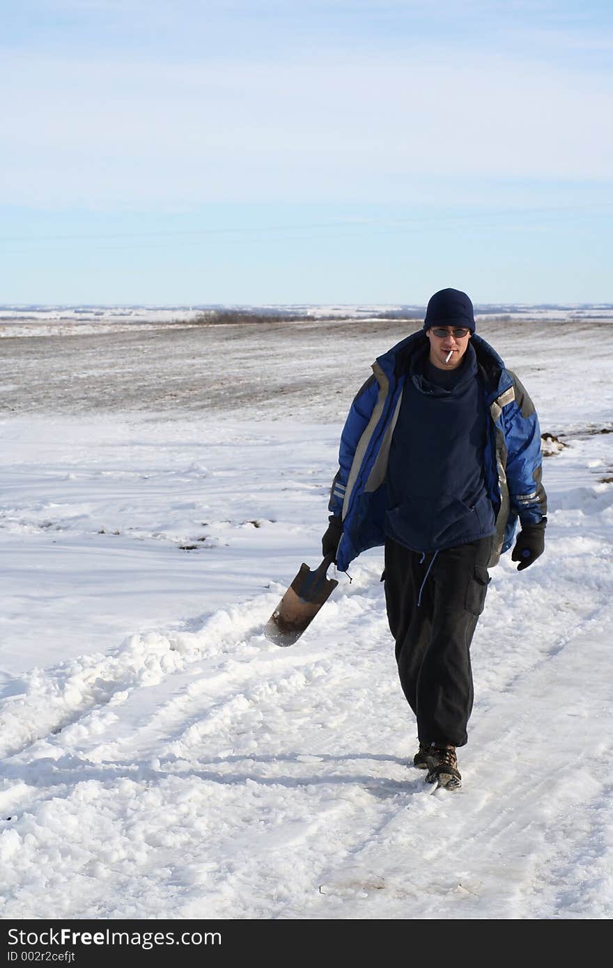 Young Man Walking with Shovel along country road