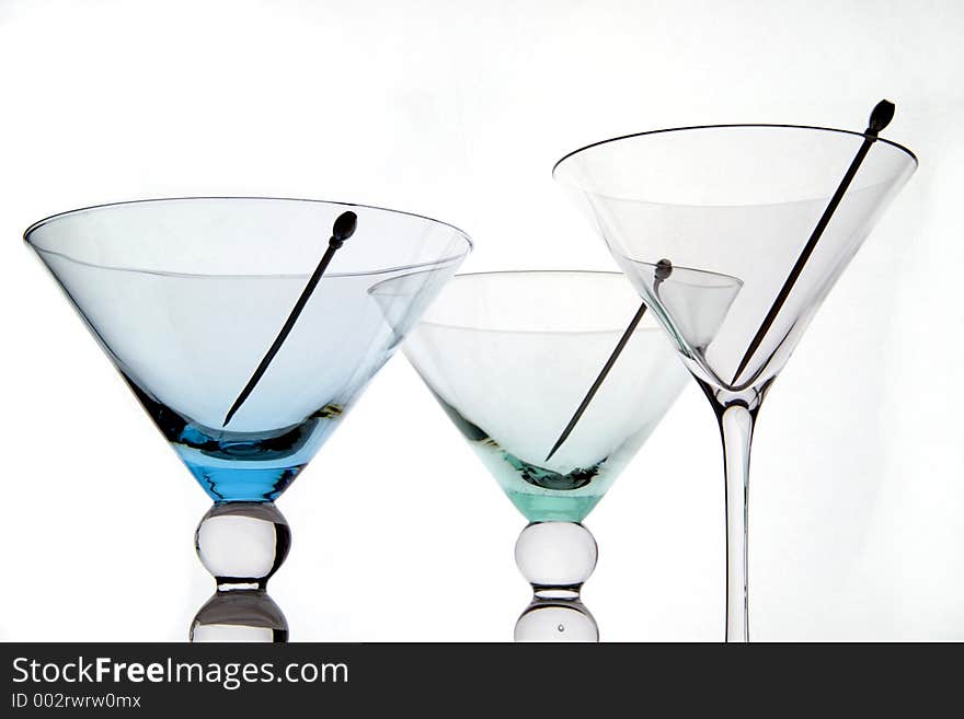 Three empty martini glasses with cocktail sticks and white background.