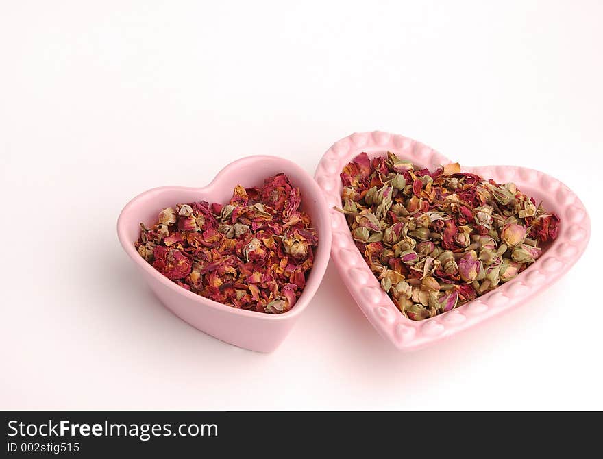 Two heart shaped dishes filled with rose petals. Two heart shaped dishes filled with rose petals