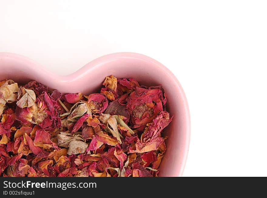 Rose petal potpourri in a pink heart shaped bowl. Rose petal potpourri in a pink heart shaped bowl