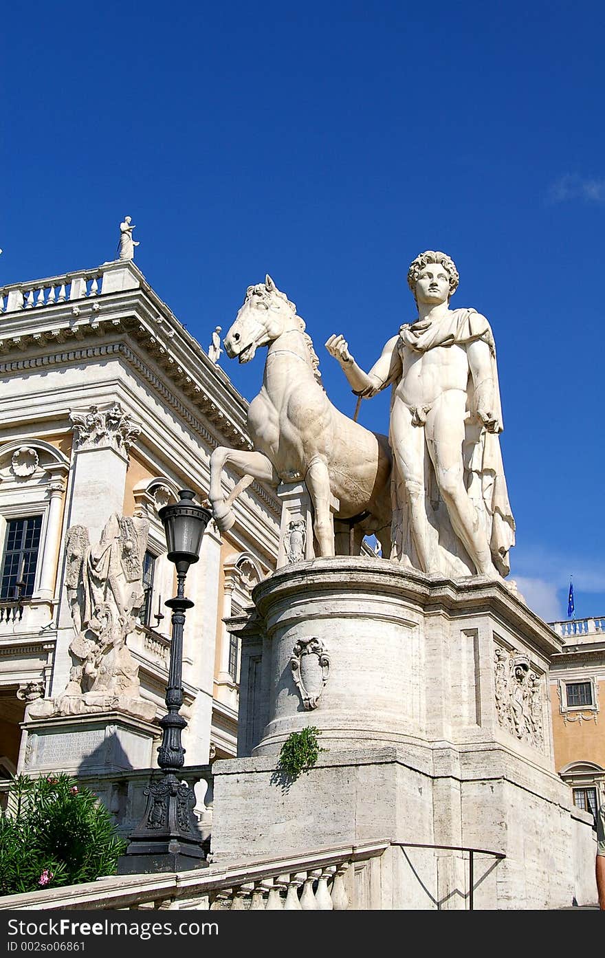 A statue of the mythological figure, Pollux, and his horse outside an ornate building. A statue of the mythological figure, Pollux, and his horse outside an ornate building.