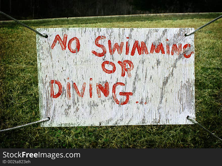 An old hand-painted sign hangs over green grass at a boat dock. An old hand-painted sign hangs over green grass at a boat dock.