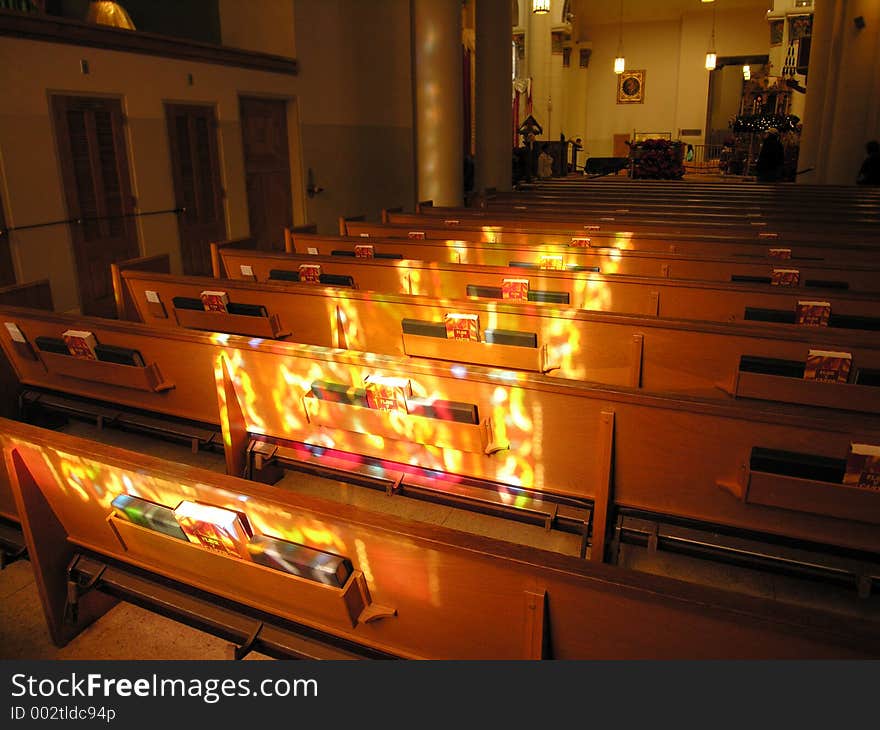 Stained glass light casts onto church pews. Stained glass light casts onto church pews.