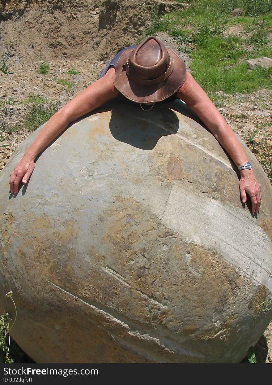 Person draped around a limestone /basalt rock ball uncovered on farmland in a quarry.perhaps from early volcanic eruption. Person draped around a limestone /basalt rock ball uncovered on farmland in a quarry.perhaps from early volcanic eruption