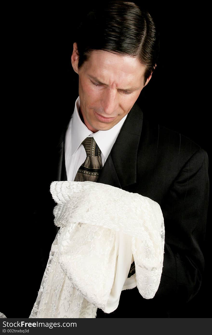 A groom left at the altar, or grieving widower, holding the empty wedding dress of his bride. A groom left at the altar, or grieving widower, holding the empty wedding dress of his bride.