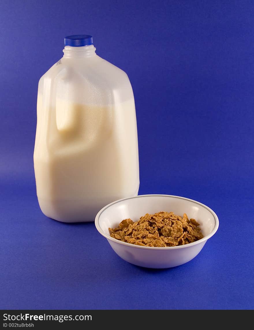 A bowl of cereal and container of milk ready for breakfast. A bowl of cereal and container of milk ready for breakfast.