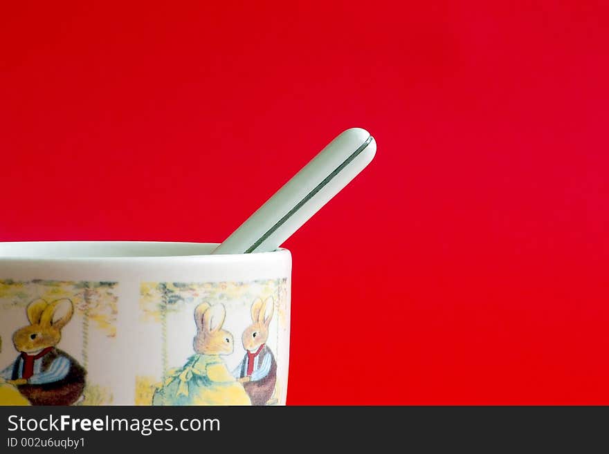 White milk cup with small spoon on a red background