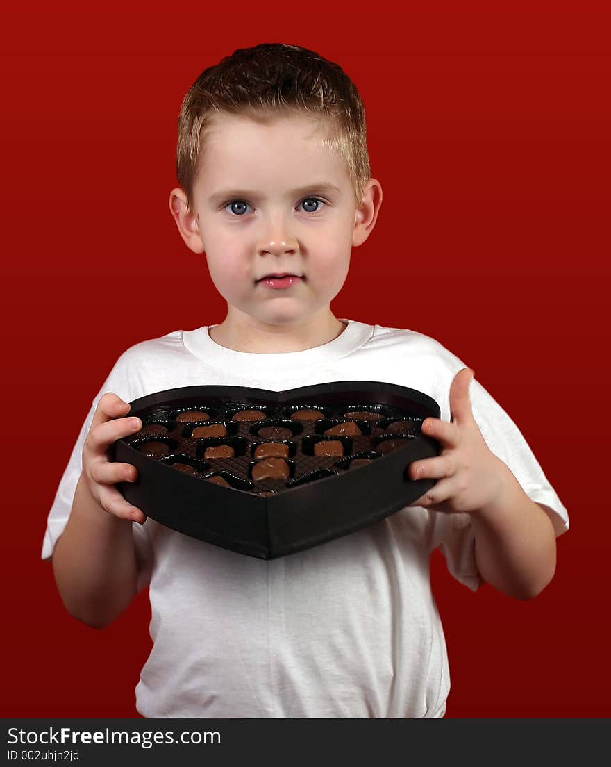 A little boy holding a heart shaped box. A little boy holding a heart shaped box.