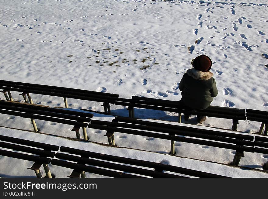 Incognito woman sitting on the bench in winter time