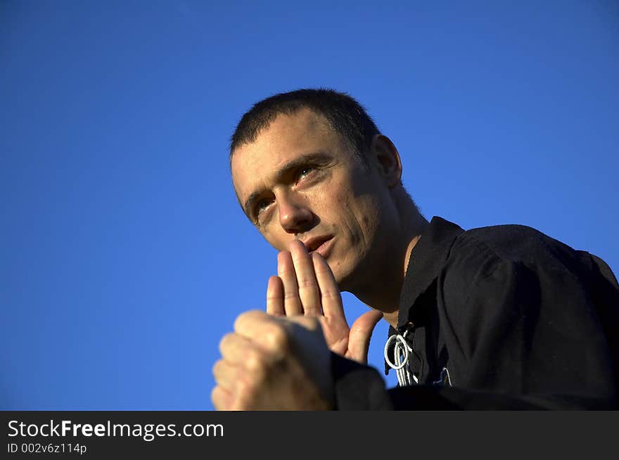 A man with a Pencak Silat pose on a sunny day with blue air in the back. A man with a Pencak Silat pose on a sunny day with blue air in the back.