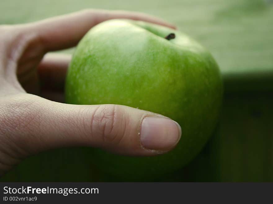 Hand holding a green apple