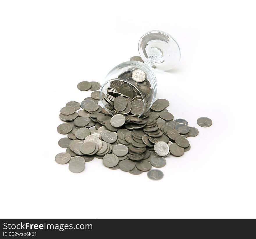 A tipped over wine glass with coins spilled on the surface. A tipped over wine glass with coins spilled on the surface